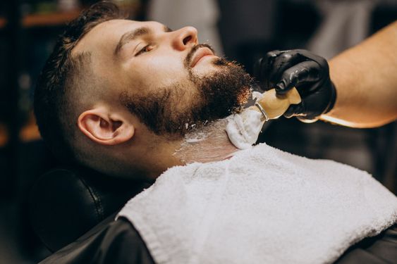 Fotografía de una persona a la que le estan colocando espuma para afeitar, en el cuello