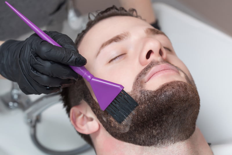 Fotografia de una persona a la que le estan colocando tinte en la barba